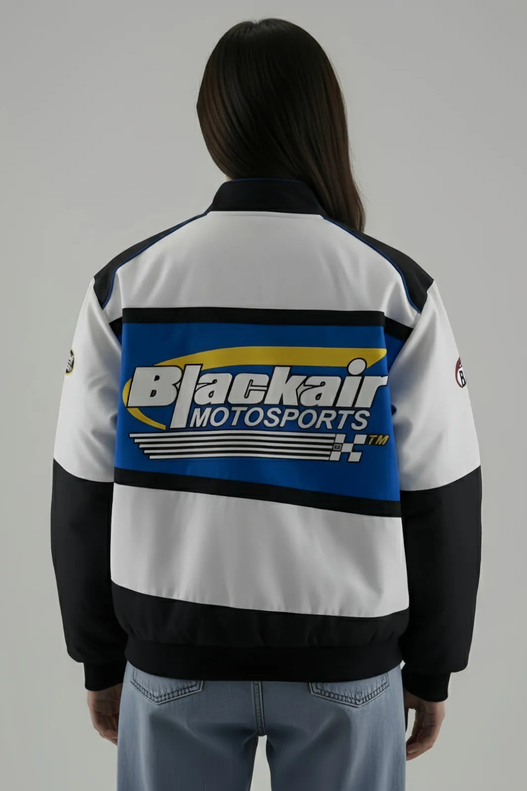 Female Model wearing a Blackair Motorsports jacket on a gray background giving back pose