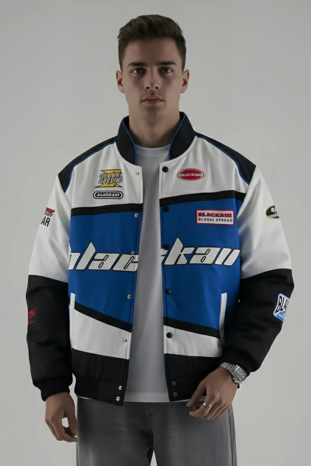 Person wearing a BlackAir Blue jacket with various brand logos on a gray background giving front pose