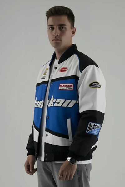 Person wearing a Black Air  racing jacket with various logos on a gray background and giving side pose
