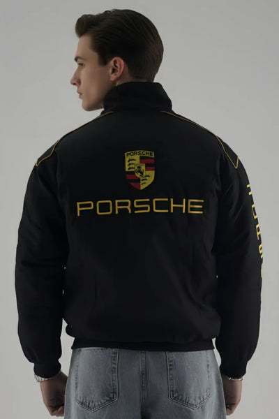 Person wearing a black Porsche jacket with logo on a gray background giving back pose