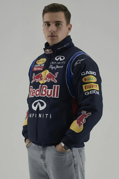 Person wearing a Red Bull F1 jacket with various sponsor logos on a gray background giving side pose 