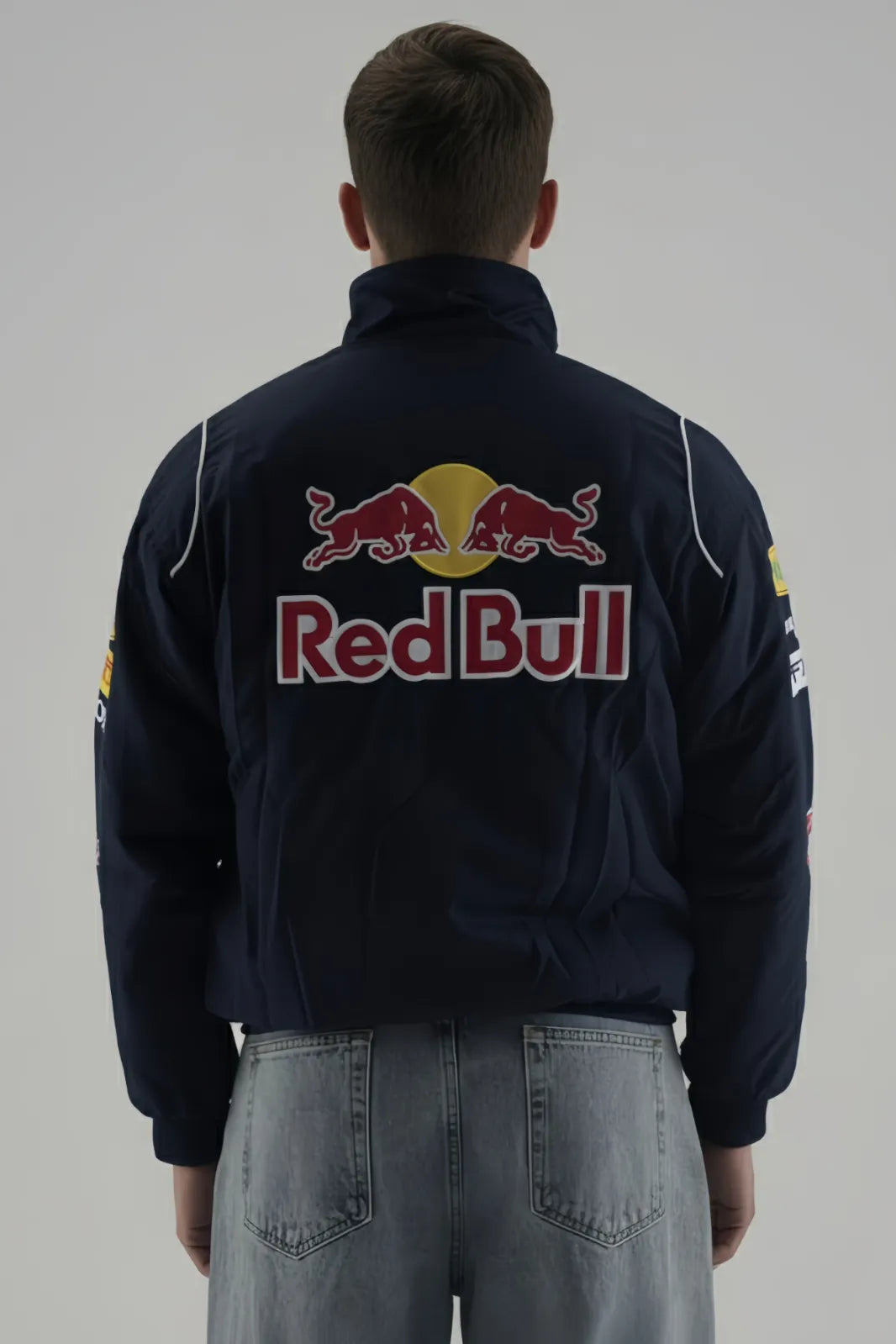 Person wearing a Red Bull F1 Jacket jacket with Red Bull logo on a plain background giving back pose 