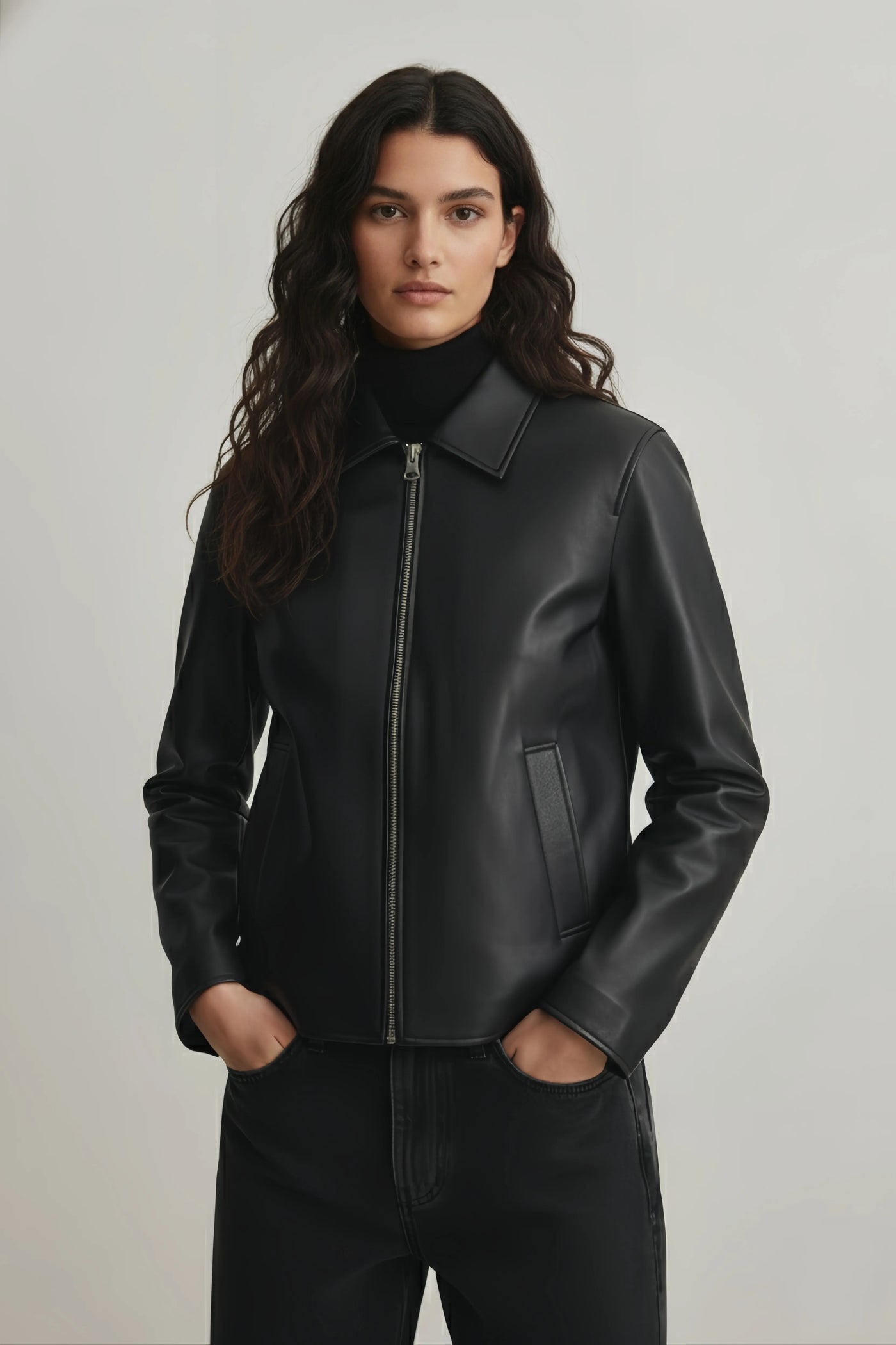 Woman wearing a black leather jacket against a plain background