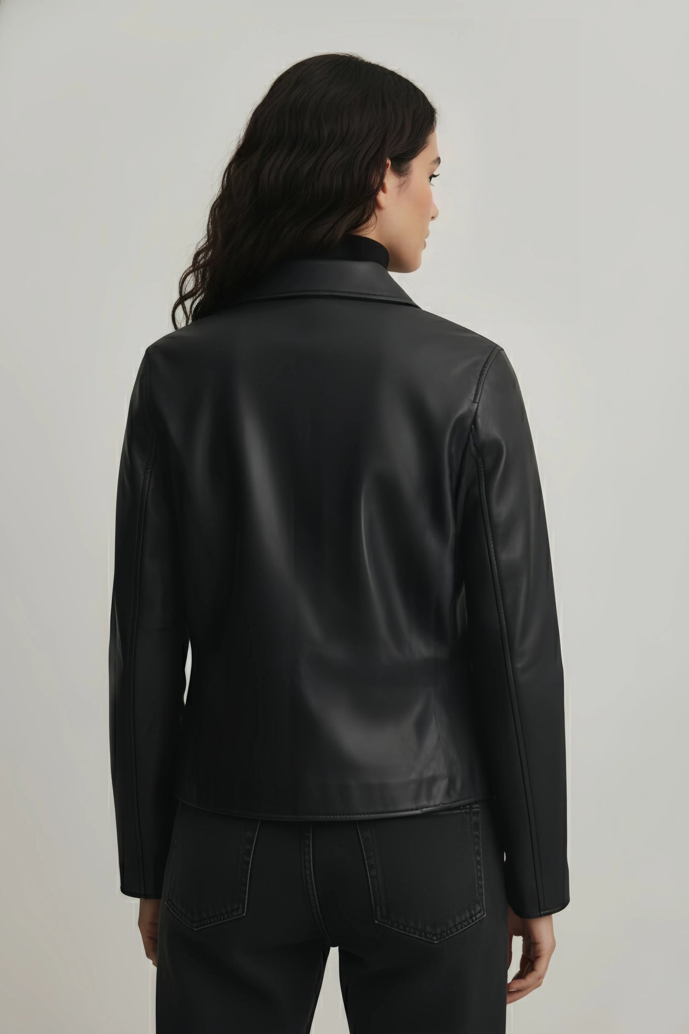 Person wearing a black leather jacket against a plain background