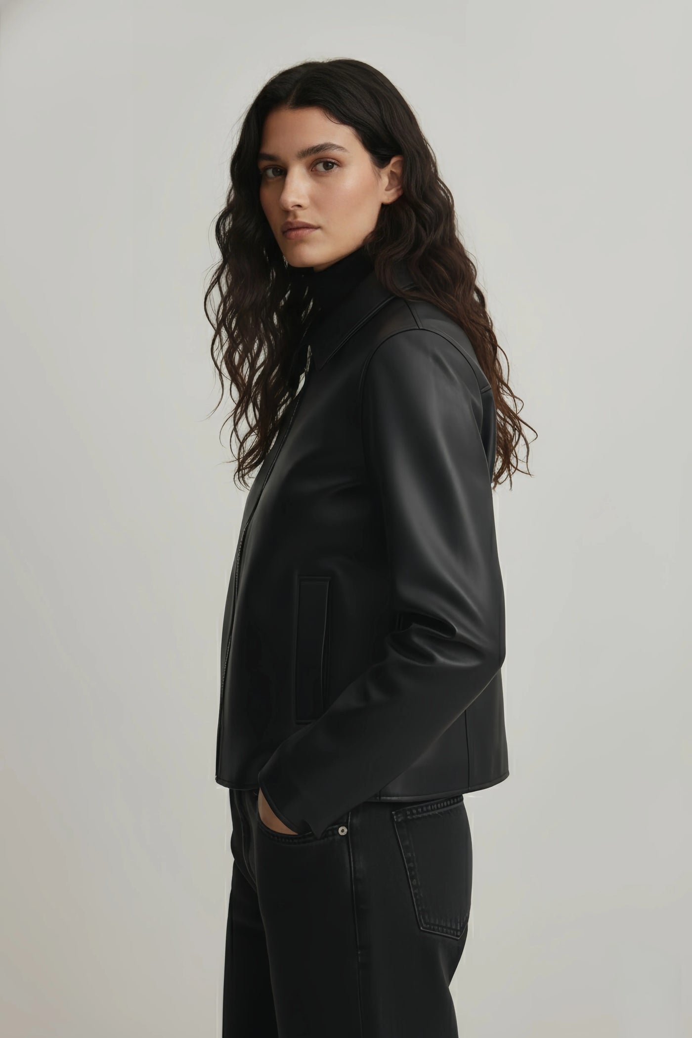 Woman wearing a black leather jacket on a plain background