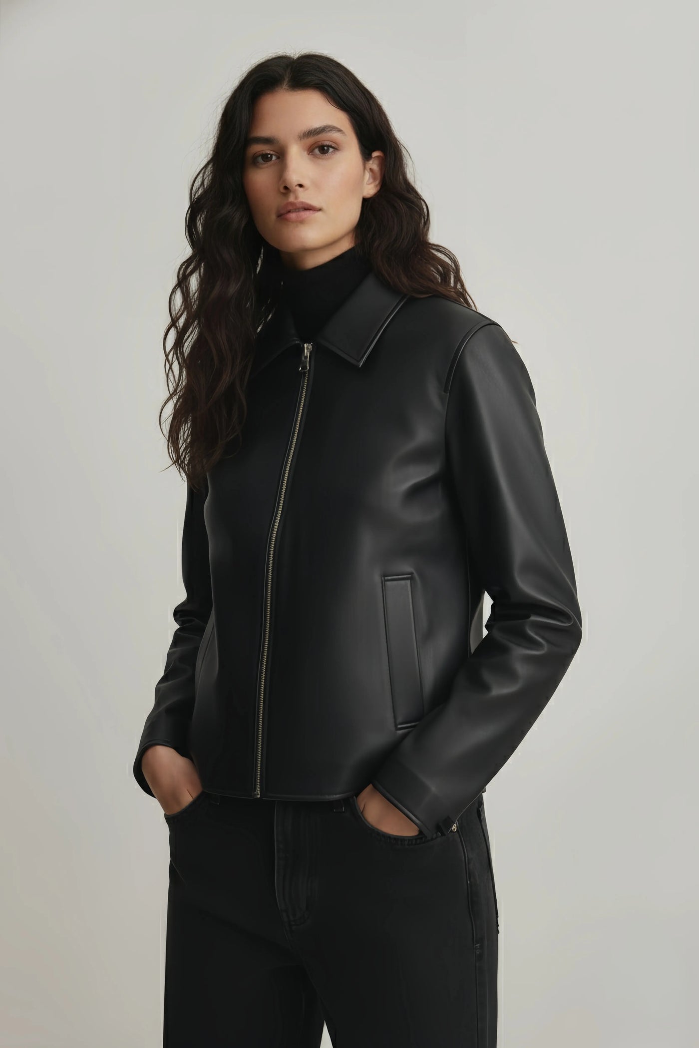 Woman wearing a black leather jacket against a plain background
