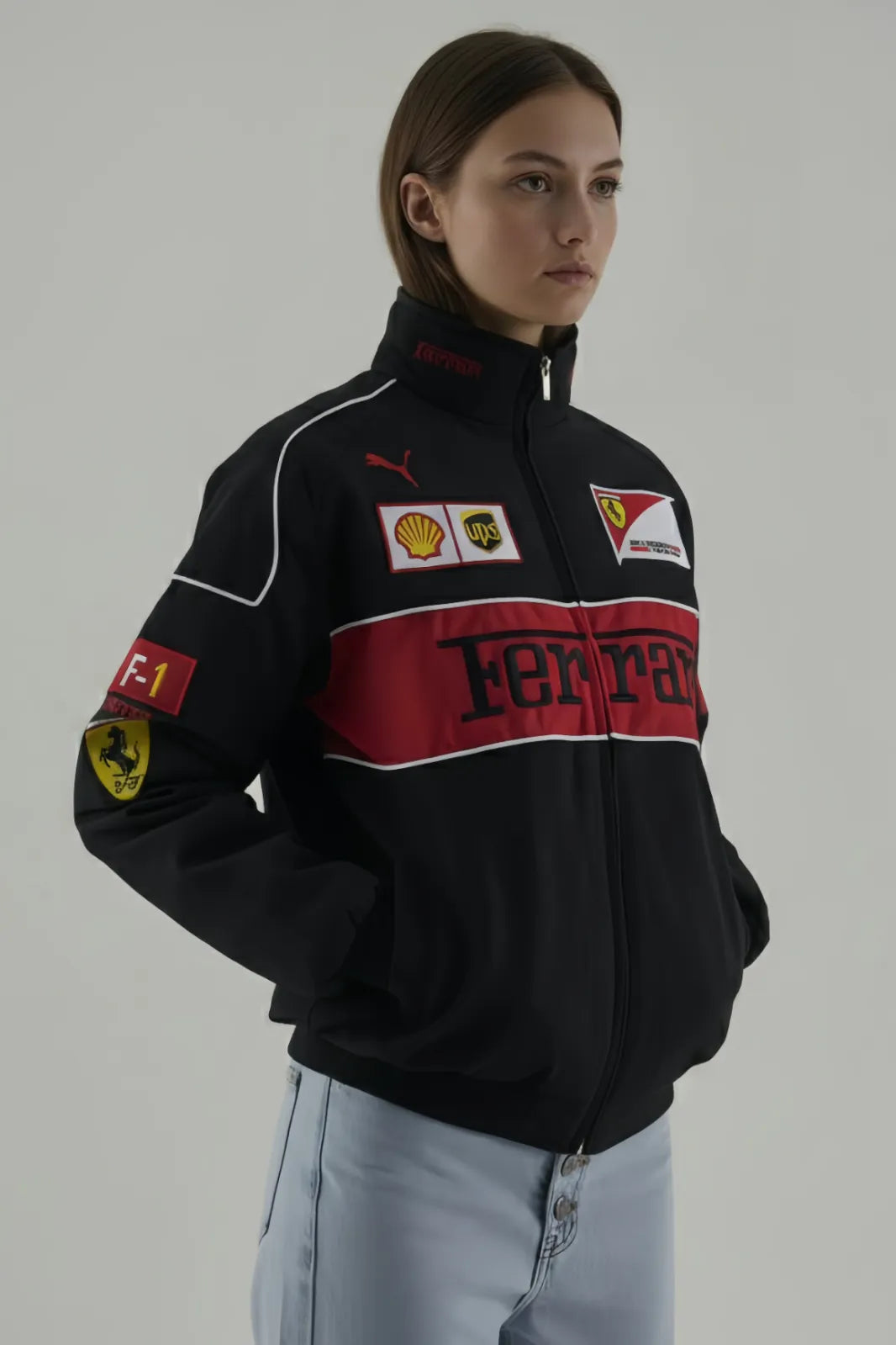 Female Model wearing a black Ferrari jacket and giving side pose with various logos on a gray background