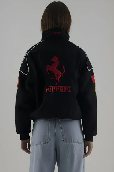Person wearing a black Ferrari jacket and giving back pose with red logo on a plain background
