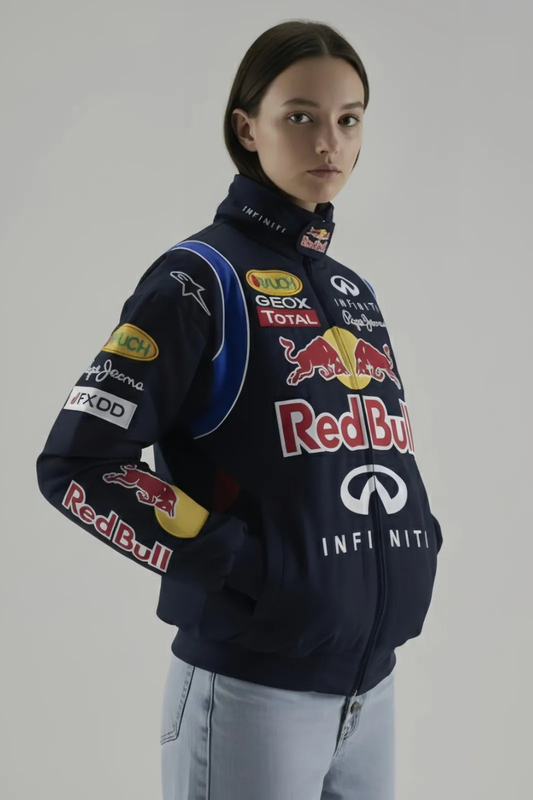 Female Model wearing a navy blue jacket with various sponsor logos on a plain background giving side pose