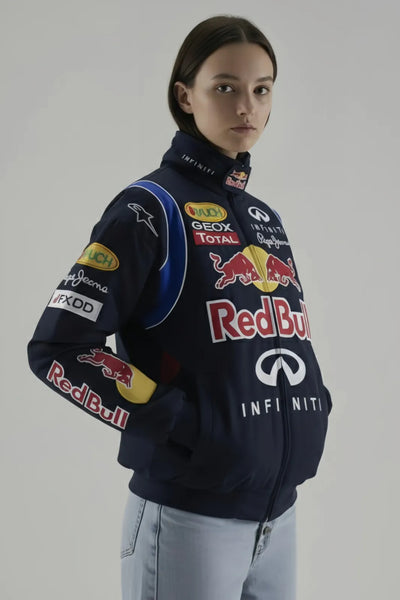 Female Model wearing a navy blue jacket with various sponsor logos on a plain background giving side pose